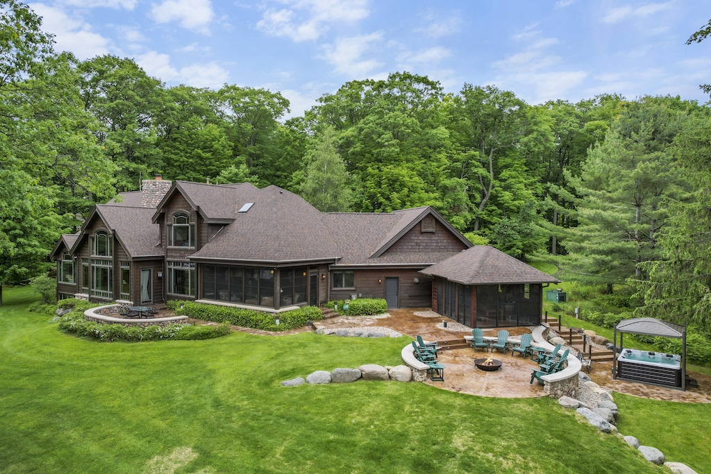 A large home in the woods with a large deck.